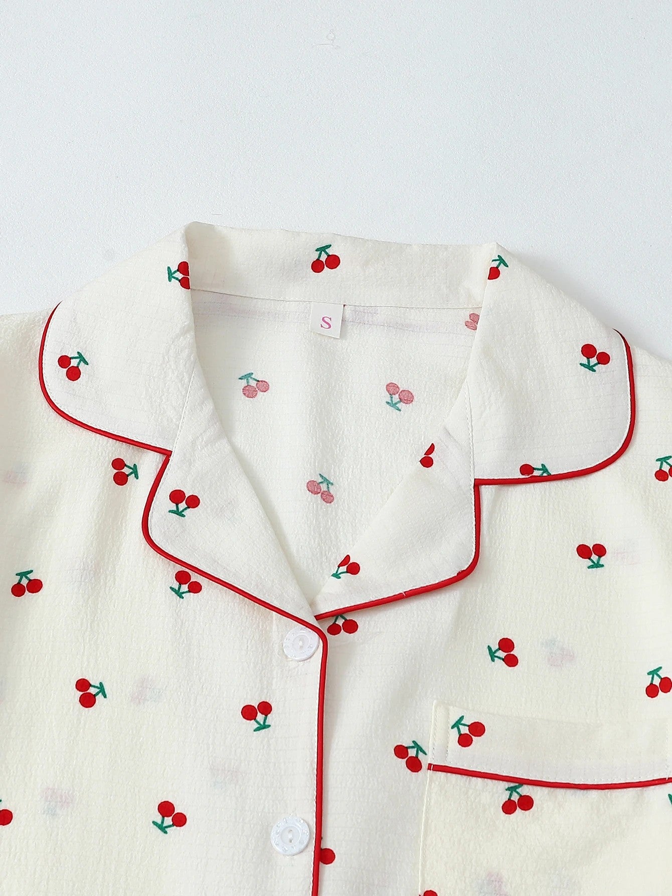 Jelly Studio cream lounge shorts with red cherry print and red piping. Relaxed fit, elastic waistband.