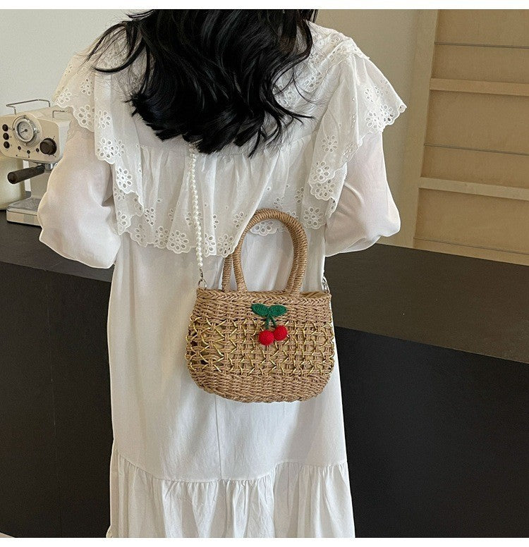 Jelly Studio woven straw handbag with cherry charm and pearl strap.