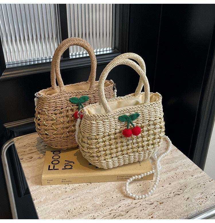 Jelly Studio woven straw handbag with cherry charm and pearl strap. Beige and tan.